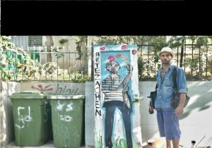איש בחולצת ג'ינס ומצלמה ליד פחי זבל ירוקים