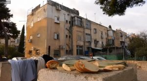 חתיכות לחם על חומה וברקע בלוק שיכונים. מתוך עבודת הוידאו "בלוק 30", פסטיבל "מדרום" 2020