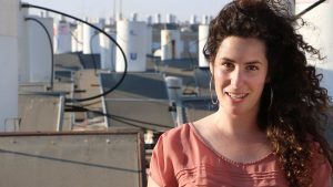 יעל רומני, יזמת פסטיבל "סרטים על שיכונים" על גג בניין עם קולטים ודודי שמש ברקע