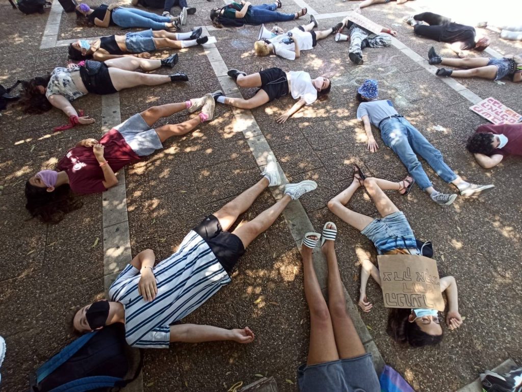 קבוצת נערים ונערות שוכבים על הקרקע, כאילו הם מתים, כמצג שמדמה אנשים שימותו בעקבות משבר האקלים