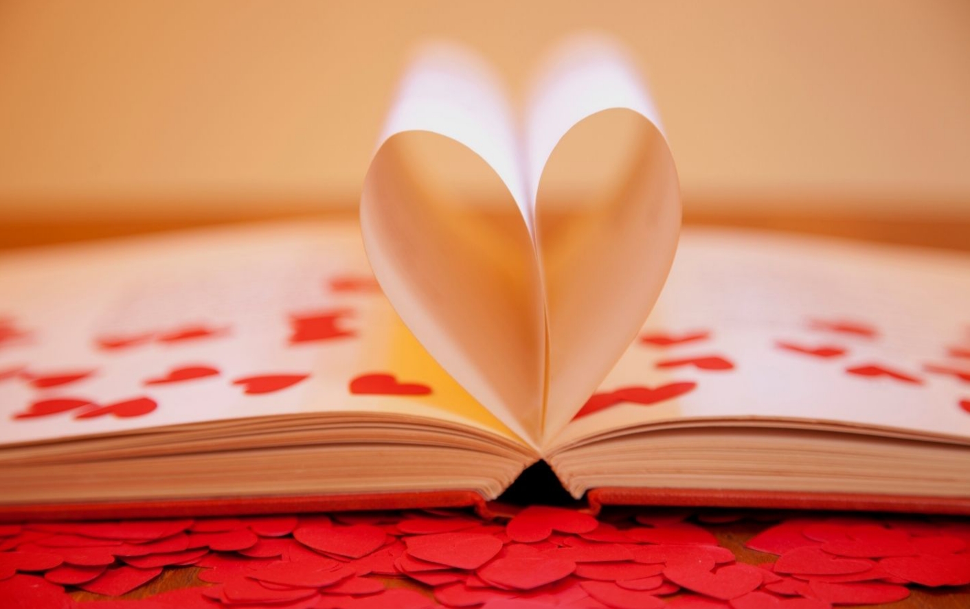 ספר פתוח שדפיו יוצרים לב. ובצד שמאל כתוב "זאת שיודעת" בצבע אדום