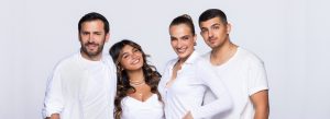 משפחת לוי שדה לבושים בלבן ומביטים למצלמה. מימין לשמאל: ליאם גולן שם את ידו הימנית בכיסו, אילנית לוי גם היא ומחייכת למצלחמה, אלין לוי מחייכת למצלמה ומניחה אתראשה על אלירז שלצידה, ששם את ידו הימנית בכיסו ומחייך למצלמה