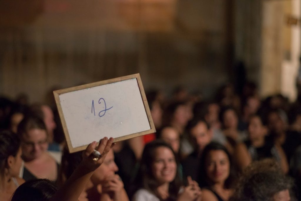 מספר 12 שרשום על לוח לבן מתנוסס באוויר כשברקע הקהל