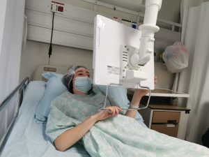 שהם יושבת על מיטת בית חולים עם חלוק ניתוחים